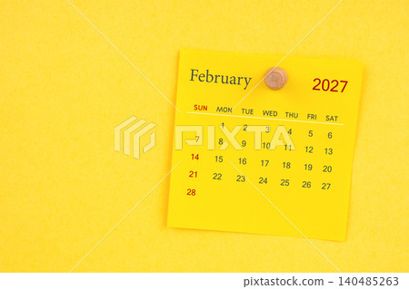 February 2027 calendar sheet with thumbtack on yellow color background. February 2027 calendar sheet with thumbtack on yellow color background. 140485263