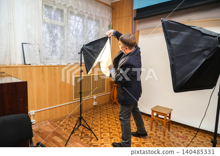 Male photographer inspecting and repairing a studio lighting equipment in a professional photo studio Male photographer inspecting and repairing a studio lighting equipment in a professional photo studio 140485331