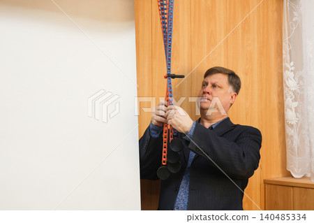 A male photographer lowers a white paper backdrop for a photo shoot in a professional studio A male photographer lowers a white paper backdrop for a photo shoot in a professional studio 140485334