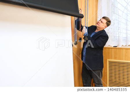 Male photographer lowering a black backdrop for a photo shoot in a professional studio setting 140485335