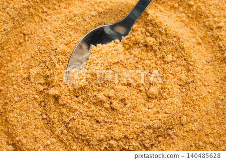 Golden cane sugar mound, spoon nestled within. Fine sweet granules  140485628
