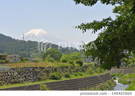 從桂川公園看到的富士山:美麗的雪山聖峰矗立在清澈的溪流和鬱鬱蔥蔥的樹木的岸邊。 從桂川公園看到的富士山:美麗的雪山聖峰矗立在清澈的溪流和鬱鬱蔥蔥的樹木的岸邊。 140485660