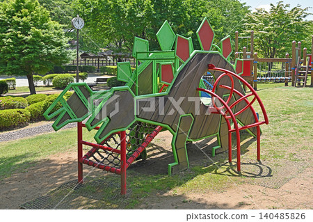 桂川公園的恐龍主題遊樂設施:色彩繽紛的運動器材被鬱鬱蔥蔥的樹木環繞,激發孩子們的冒險精神。 桂川公園的恐龍主題遊樂設施:色彩繽紛的運動器材被鬱鬱蔥蔥的樹木環繞,激發孩子們的冒險精神。 140485826