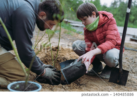 A man and his son plant a dogwood shrub on their countryside property A man and his son plant a dogwood shrub on their countryside property 140485886