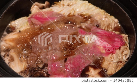 close up of a Japanese sukiyaki hot pot with simmering marbled wagyu beef, mushrooms, Enoki mushrooms, cabbage and tofu in a black pot with copy space close up of a Japanese sukiyaki hot pot with simmering marbled wagyu beef, mushrooms, Enoki mushrooms, cabbage and tofu in a black pot with copy space 140485895