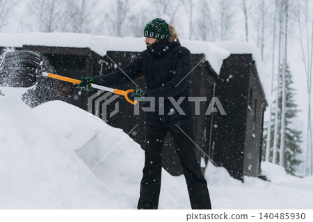 man shoveling snow with a shovel on the driveway of his countryside property during a snowfall man shoveling snow with a shovel on the driveway of his countryside property during a snowfall 140485930
