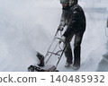 man clearing snowin countryside using electric snow blower 140485932