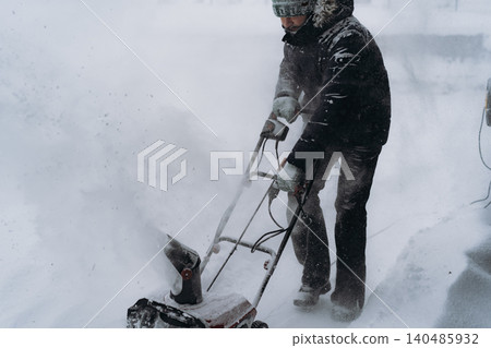 man clearing snowin countryside using electric snow blower man clearing snowin countryside using electric snow blower 140485932