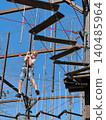 a teenage boy in outdoor rope park passing obstacle course. Active summer holidays 140485964