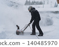 man clearing snowdrifts in countryside using electric snow blower 140485970