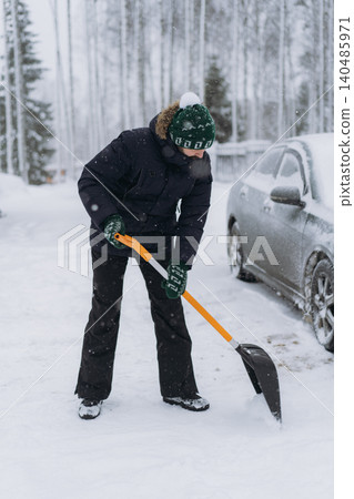 man shoveling snow with a shovel on the driveway of his countryside property during a snowfall man shoveling snow with a shovel on the driveway of his countryside property during a snowfall 140485971