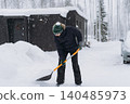 man shoveling snow with a shovel on the driveway of his countryside property during a snowfall 140485973