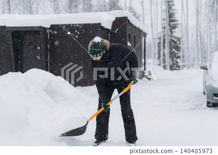 man shoveling snow with a shovel on the driveway of his countryside property during a snowfall man shoveling snow with a shovel on the driveway of his countryside property during a snowfall 140485973