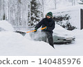 man shoveling snow with a shovel on the driveway of his countryside property during a snowfall 140485976