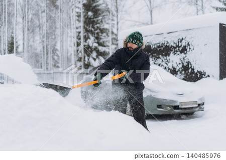 man shoveling snow with a shovel on the driveway of his countryside property during a snowfall man shoveling snow with a shovel on the driveway of his countryside property during a snowfall 140485976