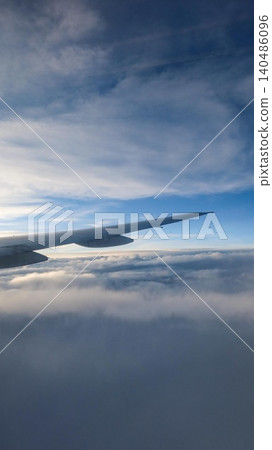 vertical photo of close up of an airplane wing view above clouds with blue sky gradient taken from the jet window, serene high-altitude flight perspective with copy space vertical photo of close up of an airplane wing view above clouds with blue sky gradient taken from the jet window, serene high-altitude flight perspective with copy space 140486096