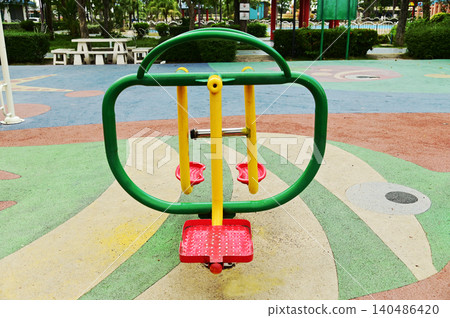 A brightly colored exercise machine. To use it, stand on the platform and swing your legs from left to right. in public parks. A brightly colored exercise machine. To use it, stand on the platform and swing your legs from left to right. in public parks. 140486420