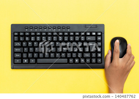 Hands type on black keyboard, mouse clicks beside. Bright yellow background adds cheerful contrast. Fingers move purposefully, suggesting focused work. Ideal for digital tasks, remote learning Hands type on black keyboard, mouse clicks beside. Bright yellow background adds cheerful contrast. Fingers move purposefully, suggesting focused work. Ideal for digital tasks, remote learning 140487762