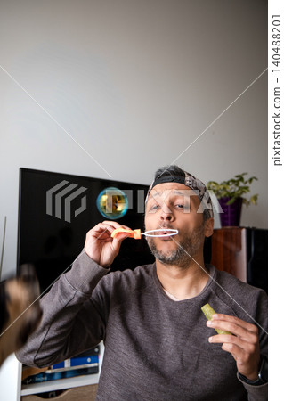 A man is blowing bubbles with a bubble wand 140488201