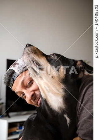 A man is hugging a dog with a brown and black coat 140488202