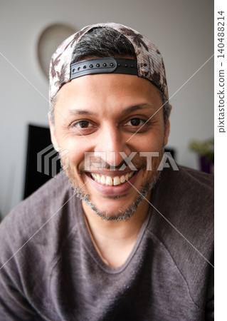 A man wearing a hat and a gray shirt is smiling A man wearing a hat and a gray shirt is smiling 140488214