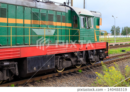 Diesel locomotive shunter train on railway tracks, green and red switcher engine side view at station yard Diesel locomotive shunter train on railway tracks, green and red switcher engine side view at station yard 140488319