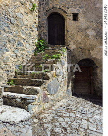 Weathered stone steps lead to a dark, arched doorway Weathered stone steps lead to a dark, arched doorway 140488346