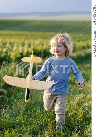 Young boy running with toy airplane in green field Young boy running with toy airplane in green field 140488796