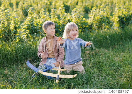 Children playing with toy airplanes in green field 140488797