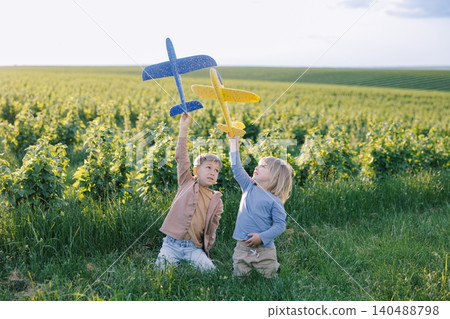 Children playing with toy gliders in green field Children playing with toy gliders in green field 140488798