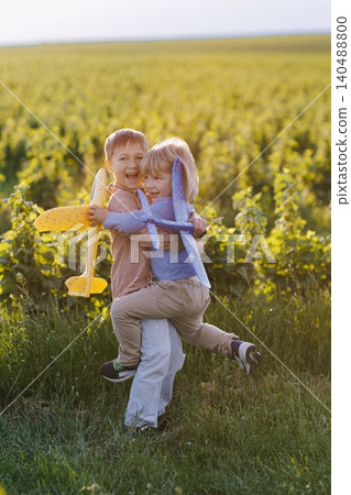 Happy children hugging playing with toy airplanes in field Happy children hugging playing with toy airplanes in field 140488800