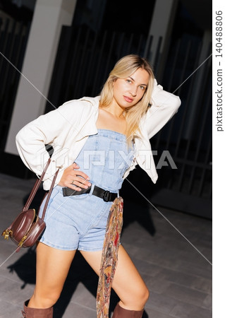 Blonde woman posing in trendy denim romper outfit Blonde woman posing in trendy denim romper outfit 140488806