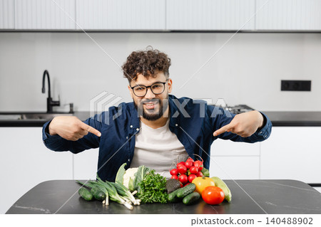 Happy man pointing at fresh vegetables in kitchen Happy man pointing at fresh vegetables in kitchen 140488902