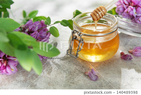 Acacia honey in glass jar with wooden dipper Acacia honey in glass jar with wooden dipper 140489398