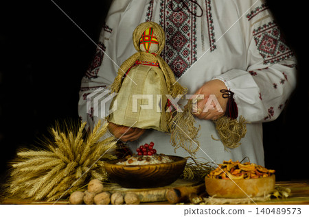 Hands in ornate ukrainian embroidered blouse stir or arrange kutia in large wooden bowl surrounded by festive natural elements. Traditional ukrainian christmas kutia preparation Hands in ornate ukrainian embroidered blouse stir or arrange kutia in large wooden bowl surrounded by festive natural elements. Traditional ukrainian christmas kutia preparation 140489573