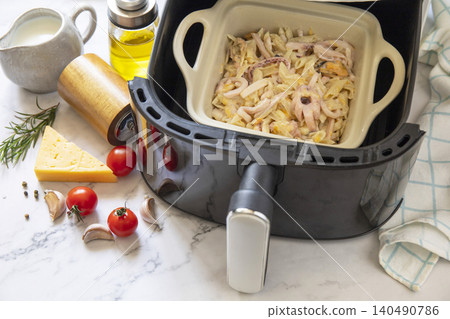 Pasta with seafood in creamy cheese sauce, in kitchen gadget modern white air fryer. Lifestyle trendy of new cooking. Copy space. Pasta with seafood in creamy cheese sauce, in kitchen gadget modern white air fryer. Lifestyle trendy of new cooking. Copy space. 140490786