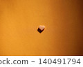 A flatlay of small heart-shaped chocolates placed against a background of similar colors. 140491794