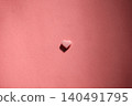A flatlay of small heart-shaped chocolates placed against a background of similar colors. 140491795