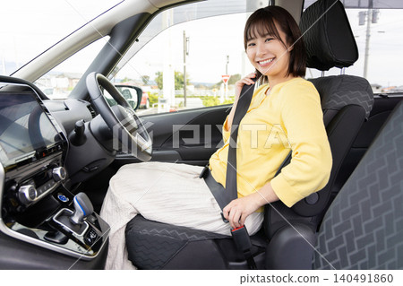 A smiling female driver wearing a seatbelt inside the car. A smiling female driver wearing a seatbelt inside the car. 140491860