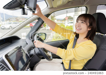 一位面帶微笑的女司機正在操作行車記錄器。 一位面帶微笑的女司機正在操作行車記錄器。 140491863