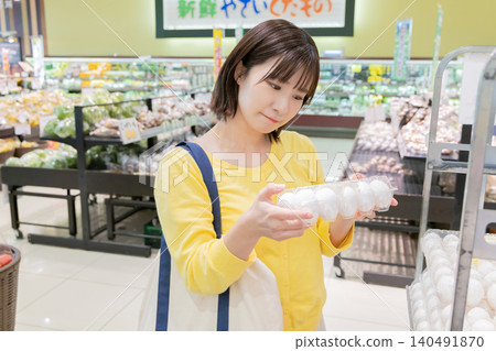 一位微笑的女士在超市挑選雞蛋。 一位微笑的女士在超市挑選雞蛋。 140491870