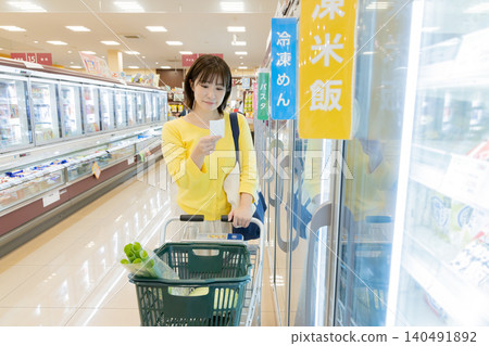 一位女士正在超市冷凍食品區購物。 一位女士正在超市冷凍食品區購物。 140491892