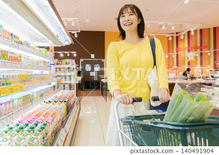 一位面帶微笑的年輕女子正在超市購物。 一位面帶微笑的年輕女子正在超市購物。 140491904