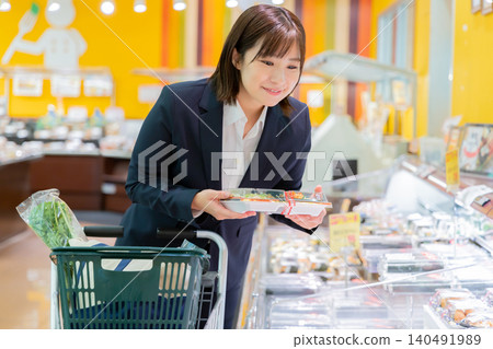 A businesswoman shopping in the prepared food section of a supermarket. A businesswoman shopping in the prepared food section of a supermarket. 140491989