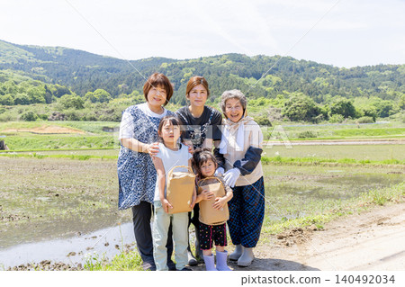 Three generations of Japanese women and their children smile as they hold their harvested produce in a rice paddy in a rural area. Three generations of Japanese women and their children smile as they hold their harvested produce in a rice paddy in a rural area. 140492034