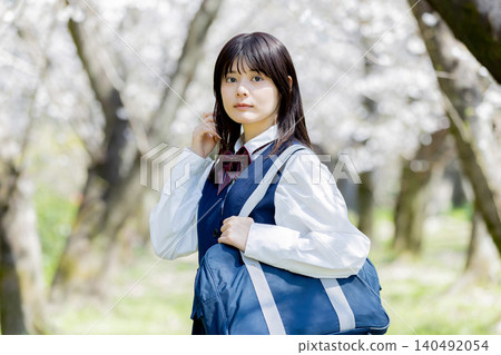 A spring portrait of a high school girl smiling amidst a row of cherry blossom trees. A spring portrait of a high school girl smiling amidst a row of cherry blossom trees. 140492054