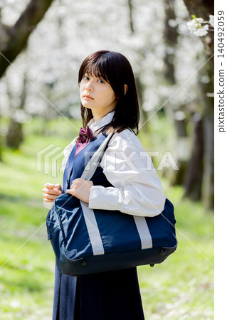 A spring portrait of a high school girl walking along a cherry blossom-lined street. A spring portrait of a high school girl walking along a cherry blossom-lined street. 140492059