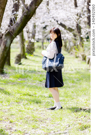 A spring portrait of a high school girl looking back at the cherry blossom trees on her way to school. A spring portrait of a high school girl looking back at the cherry blossom trees on her way to school. 140492060