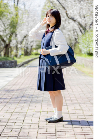 A portrait of a high school girl standing on a cherry tree-lined school route. A portrait of a high school girl standing on a cherry tree-lined school route. 140492066