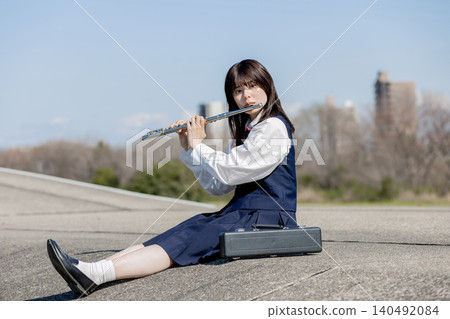 A high school girl playing the flute under the blue sky. A high school girl playing the flute under the blue sky. 140492084